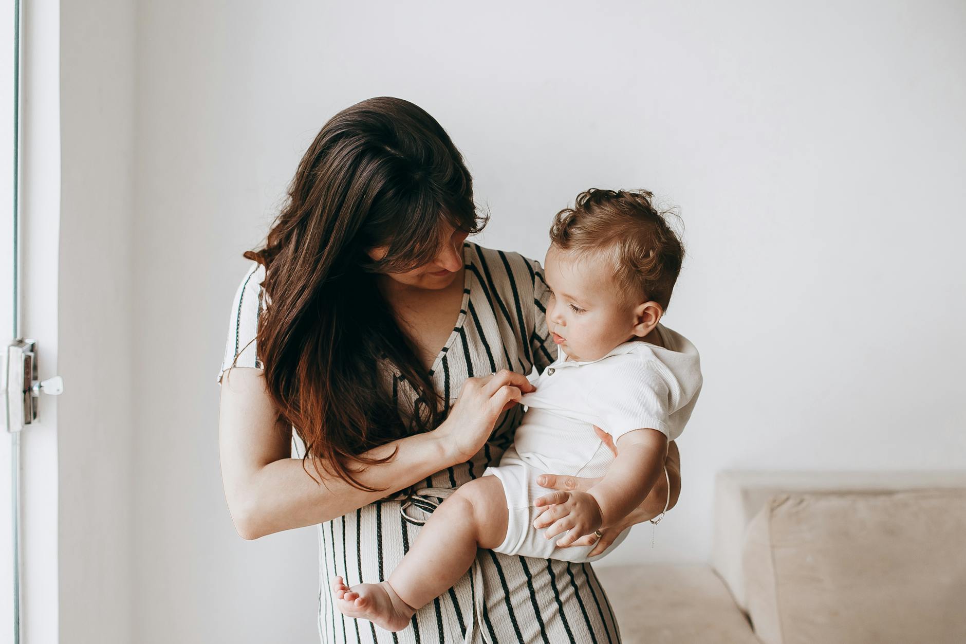 Mama delikatnie przytula niemowlę w domu