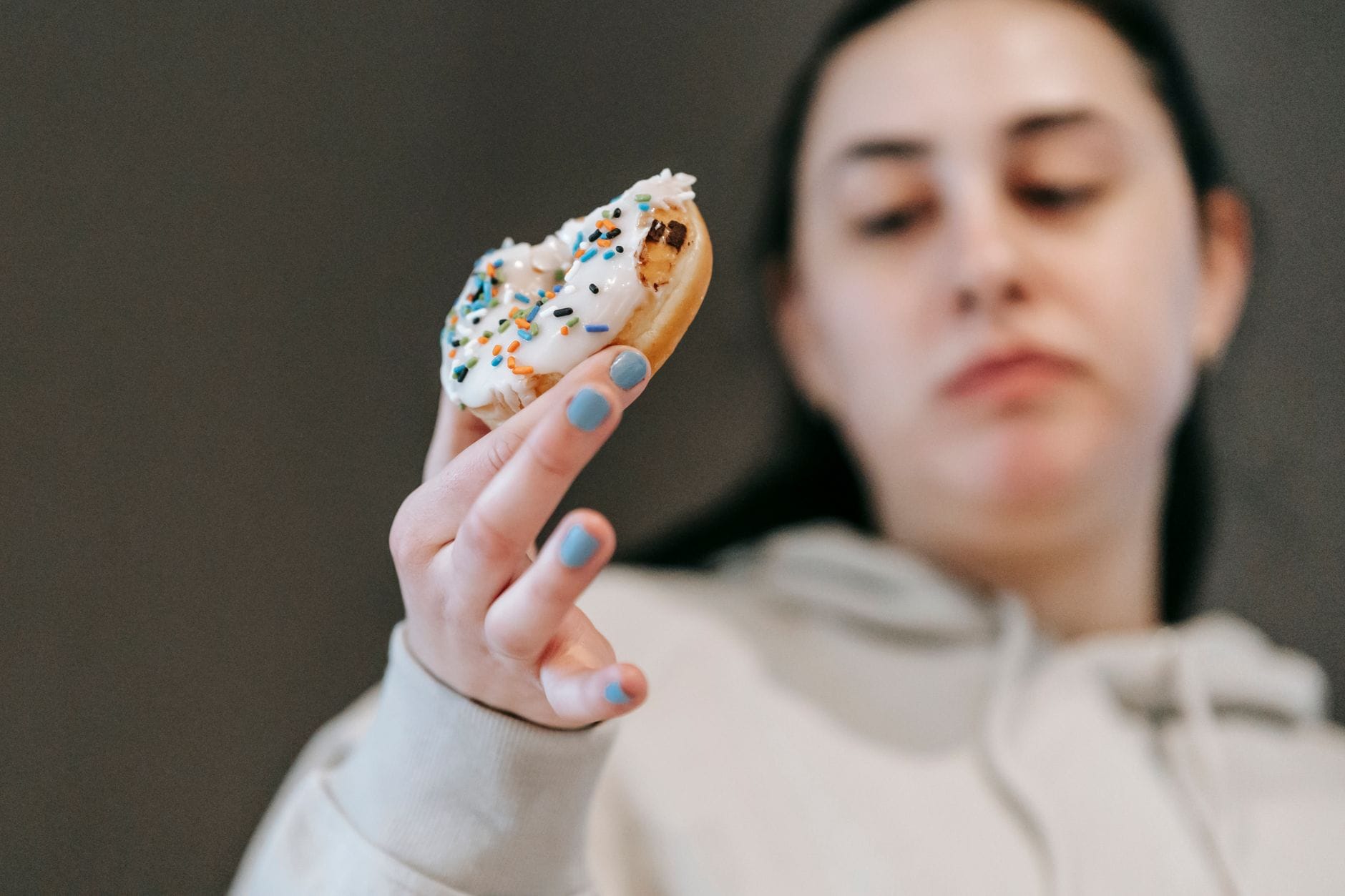 Kobieta w casualowym stroju je pączka z białym lukrem w jasnym wnętrzu